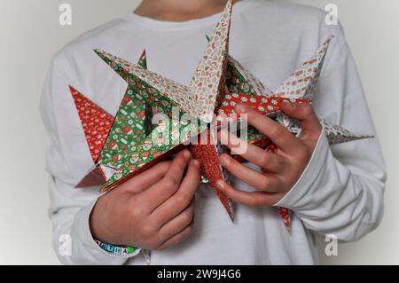 Une photo de studio d'un enfant tenant une collection d'étoiles d'origami faite de papier origami festif Banque D'Images