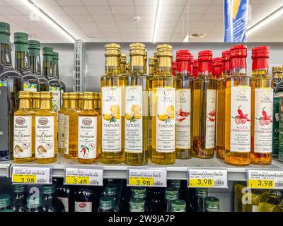 Italie - 28 décembre 2023 : huile d'olive aromatisée à la truffe et au piment dans des bouteilles en verre de différents types et marques affichées sur l'étagère à vendre Banque D'Images