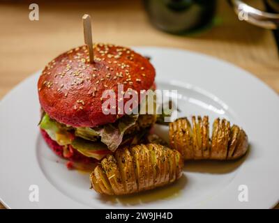 Délicieux hamburger végétarien dans un petit pain à la betterave avec des pommes de terre tranchées Banque D'Images