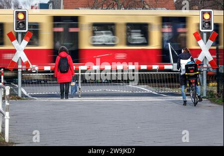 Deux femmes attendant à un passage à niveau avec une barrière pendant qu'un train S-Bahn passe à travers, Berlin, 10 01 2023 Banque D'Images