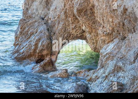 Arche dans une formation rocheuse sur le rivage avec la mer entrant par l'écart Banque D'Images