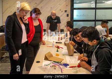 Un enseignant encourage les étudiants multiraciaux à expérimenter avec des dispositifs de technologie médicale dans une semina de démonstration de l'installation medtech d'Irvine, Californie Banque D'Images