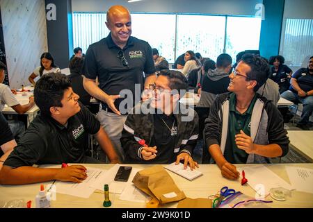 Un enseignant encourage les étudiants multiraciaux à expérimenter avec des dispositifs de technologie médicale dans une semina de démonstration de l'installation medtech d'Irvine, Californie Banque D'Images