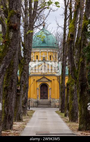 Ruelle bordée d'arbres vers le bâtiment jaune de la chapelle orthodoxe des saints apôtres Saints Pierre et Paul sur le cimetière Mirogoj à Zagreb, Croatie Banque D'Images