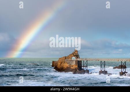 Vue lointaine du Rocher de la Vierge à Biarritz, France, après la pluie, avec un bel arc-en-ciel sur l'océan Atlantique Banque D'Images