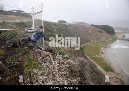 Princeton, États-Unis. 28 décembre 2023. Un spectateur avec deux chiens fait son chemin autour d'une clôture de sécurité pour voir le Mavericks Big Wave Invitational depuis les falaises autour de la Pillar point Air Force Station à Princeton, Californie, le jeudi 28 décembre 2023. La météo empêchait la plupart des gens d'avoir une vue dégagée. Photo de Terry Schmitt/UPI crédit : UPI/Alamy Live News Banque D'Images