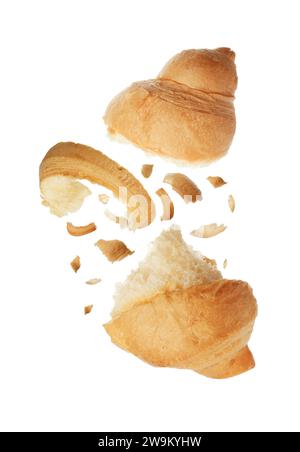 Morceaux de délicieux croissant frais tombant sur fond blanc Banque D'Images