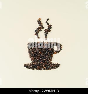 Composition créative avec tasse de vapeur de forme de café faite de grains de café torréfiés sur fond de crème légère. Aspect esthétique réaliste. Banque D'Images