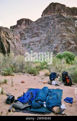 Enfants dormant dehors sur le sol à l'aube, près de Hermit Rapids sur le fleuve Colorado, au fond du Grand Canyon, Arizona, USA Banque D'Images