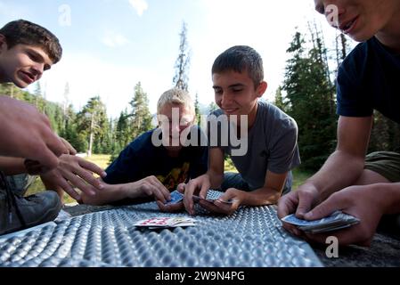 Un groupe de garçons jouent à un jeu de cartes dans leur camp de six Mile Meadow le jour 2 de leur randonnée à travers Eagle Cap Wilderness dans le nord-est de l'Oregon. Banque D'Images