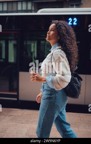 Femme sud-américaine aux cheveux bouclés buvant du café dans la rue Banque D'Images