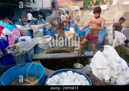 Un dhobi (laveur) à Walkeshwar Dhobi Ghat, une buanderie traditionnelle en plein air, tire l'eau du puits de la région. À Walkeshwar, Mumbai, Inde Banque D'Images