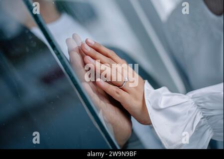 le romantisme des mains de deux couples pressées contre le verre. La main de la femme porte une bague de mariage et une robe blanche, tandis que la main de son partenaire l'est Banque D'Images