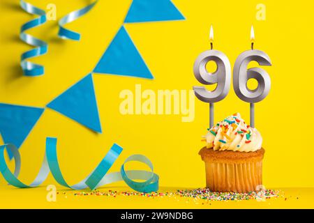 Bougie d'anniversaire numéro 96 avec cupcake - fond jaune avec fanions bleus Banque D'Images