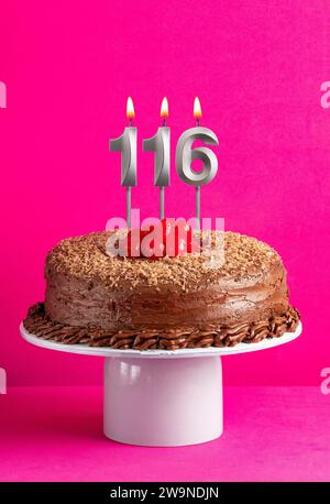 Carte d'anniversaire avec bougie numéro 116 - gâteau au chocolat sur fond rose Banque D'Images