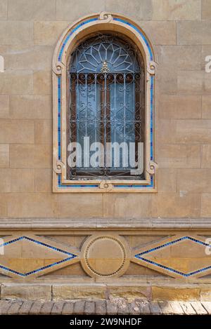 Fenêtre arquée simple de style archirtecture mamelouk encadrée par un mur de briques rustiques. Les grilles complexes en fer forgé ajoutent une touche d'élégance et de sécurité au facadey Banque D'Images