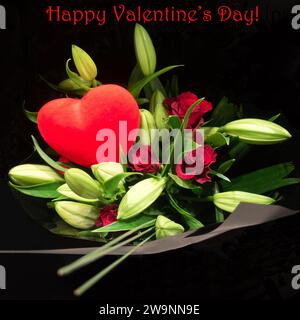 Texte de bonne Saint-Valentin écrit en caractères rouges au-dessus d'un bouquet de fleurs enveloppé contenant des roses rouges, une découpe en forme de cœur rouge et un feuillage vert. Banque D'Images
