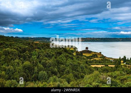 Prairies et forêts au Canal Dalcahue avec Curaco de Velez ville au bout de la baie, île de Chiloe, Chili Banque D'Images