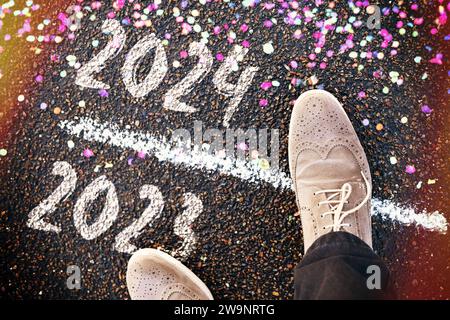 FOTOMONTAGE, Schuhe stehen auf der Schwelle zwischen 2023 und 2024 mit Konfetti, Symbolfoto Jahreswechsel *** PHOTOMONTAGE, chaussures debout sur le seuil entre 2023 et 2024 avec des confettis, photo symbolique du tournant de l'année Banque D'Images