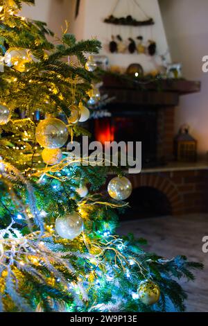 Plongez dans l'esprit des fêtes avec cette photo enchanteresse représentant des boules sur un sapin caucasien. Des lumières de Noël floues et un décor festif rehaussent le décor Banque D'Images