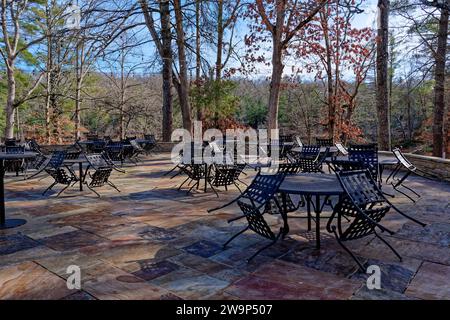 Un restaurant extérieur patio dans un parc fermé avec une table en métal extérieure et des chaises en grappes sur un sol en pierre plat coloré et avec lumière suspendue Banque D'Images