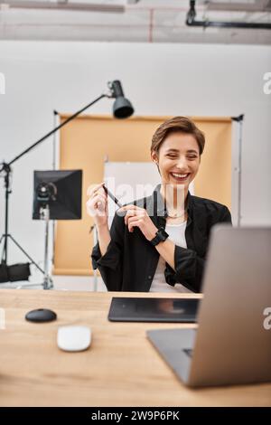 joyeuse designer professionnelle en tenue décontractée travaillant avec sa tablette de dessin en studio Banque D'Images