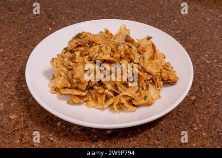 Kottu roti sri-lankais sur une plaque blanche sur fond noir Banque D'Images