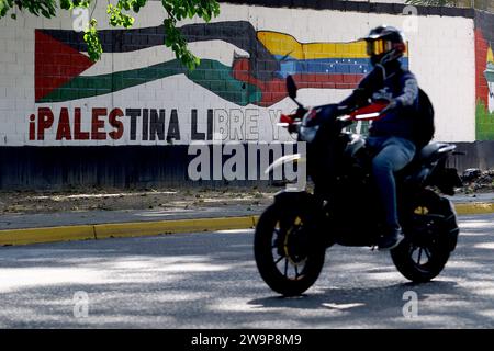 Valence, Carabobo, Venezuela. 29 décembre 2023. 29 décembre 2023. Un motocycliste monte devant un graffiti de deux mains entrelacées, symbolisant l'amitié avec les drapeaux de la Palestine, situé dans la ville de Valence, dans l'État de Carabobo. Photo : Juan Carlos Hernandez (image de crédit : © Juan Carlos Hernandez/ZUMA Press Wire) USAGE ÉDITORIAL SEULEMENT! Non destiné à UN USAGE commercial ! Crédit : ZUMA Press, Inc./Alamy Live News Banque D'Images