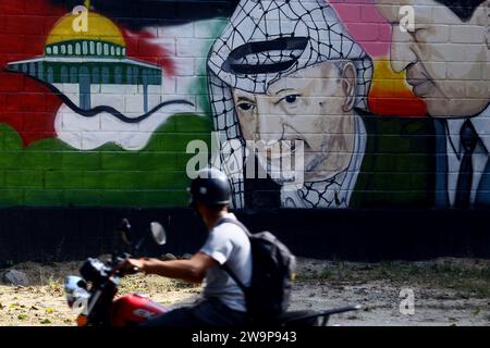 Valence, Carabobo, Venezuela. 29 décembre 2023. 29 décembre 2023. Un motocycliste monte devant un graffiti avec les images des dirigeants décédés Yasser Arafat, de Palestine, et Hugo Chavez, du Venezuela, symbolisant l'amitié avec les drapeaux de Palestine, situés dans la ville de Valence, dans l'État de Carabobo. Photo : Juan Carlos Hernandez (image de crédit : © Juan Carlos Hernandez/ZUMA Press Wire) USAGE ÉDITORIAL SEULEMENT! Non destiné à UN USAGE commercial ! Crédit : ZUMA Press, Inc./Alamy Live News Banque D'Images