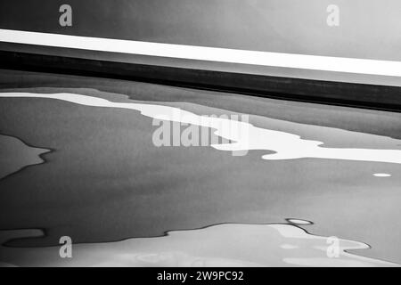 Image en noir et blanc d'une coque de yacht réfléchissant sur l'eau calme. Banque D'Images