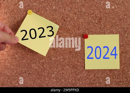 une main d'homme tirant une note collante. évolution de l'année de 2023 à 2024. idée de conseil de 2024 ans. Banque D'Images