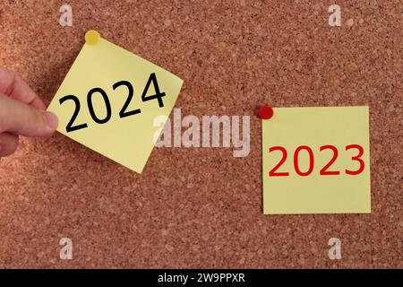 une main d'homme tirant une note collante. évolution de l'année de 2023 à 2024. idée de conseil de 2024 ans. Banque D'Images