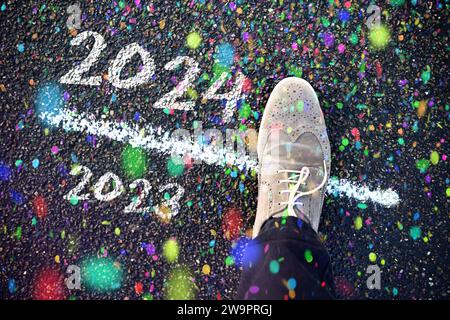 Chaussure est sur le seuil entre 2023 et 2024 avec confettis, symbole photo nouvel an, photo montage Banque D'Images