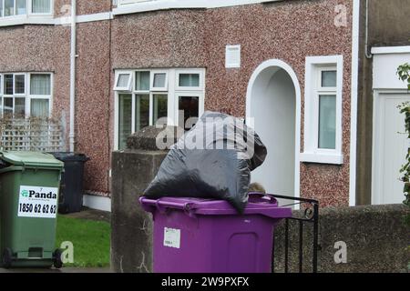 Dublin, Irlande - 27 décembre 2023 : une photo d'un sac poubelle noir plein sur un bac à compost violet dans la rue. Banque D'Images