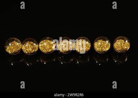 perles avec paillettes dorées sur un fond miroir noir. Banque D'Images