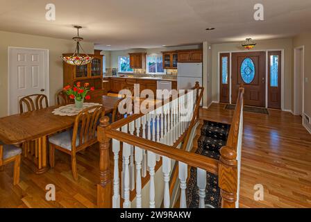 Une salle à manger, une cuisine et une cage d'escalier avec balustrades mettent en valeur cette riche rénovation de maison en bois, avec des balustrades blanches. Banque D'Images