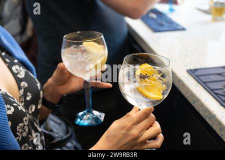 Une femme tenant deux verres de gin-tonic avec une tranche d'orange et d'anis étoilé au début d'une visite de la distillerie Bombay Sapphire. ROYAUME-UNI Banque D'Images