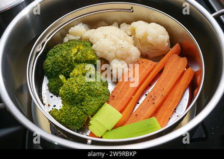 Mélange de légumes, carottes, brocolis et chou-fleur dans un panier cuiseur vapeur dans une casserole en acier inoxydable, méthode de cuisson saine préservant les minéraux, vi Banque D'Images