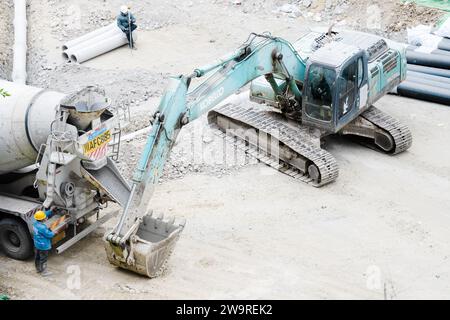 Les tuyaux sont arrosés avec des camions de ciment et des camions excavateurs Banque D'Images
