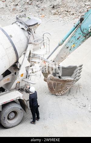 Les tuyaux sont arrosés avec des camions de ciment et des camions excavateurs Banque D'Images