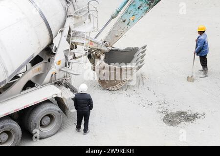 Les tuyaux sont arrosés avec des camions de ciment et des camions excavateurs Banque D'Images