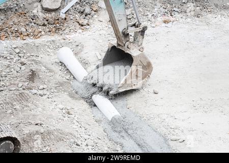 Les tuyaux sont arrosés avec des camions de ciment et des camions excavateurs Banque D'Images