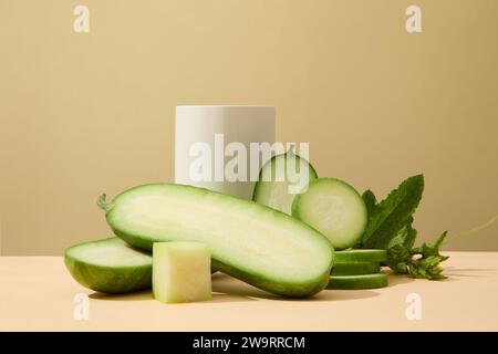 Podium blanc en forme de cylindre décoré sur fond beige avec des tranches de melon d'hiver. Le melon d'hiver (Benincasa hispida) est une excellente source de Banque D'Images