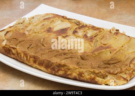 Une vue rapprochée d'un bord brun doré et légèrement croustillant d'une tarte aux pommes fraîchement cuite avec un léger saupoudrage de cannelle sur les couches superposées de Banque D'Images