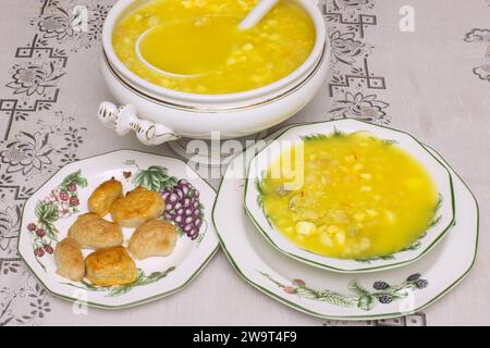 Soupe traditionnelle de poisson et de crustacés avec des palourdes visibles, du safran, des crevettes et d'autres ingrédients servis dans une tureen porcelaine et des assiettes sur un élégant t Banque D'Images