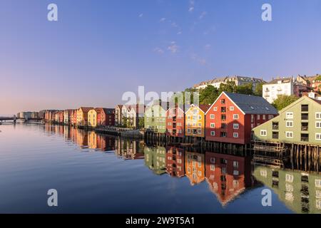 Lueur nocturne sur la rivière Nidelva avec de célèbres maisons en bois le long de son rivage lors d'un coucher de soleil d'été à Trondheim, en Norvège Banque D'Images