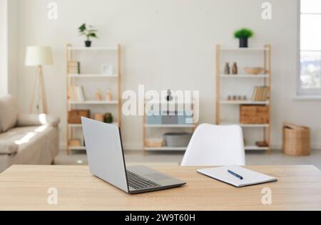Gros plan du lieu de travail vide du bureau en bois avec ordinateur portable et bloc-notes Banque D'Images