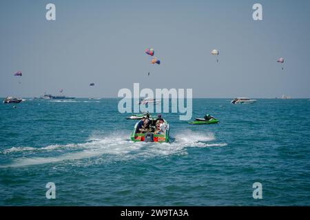 Pattaya, Thaïlande. 27 décembre 2023. Un bateau transportant des touristes pour des activités nautiques est vu sur la mer, avec en arrière-plan des touristes jouant au parachute ascensionnel à Pattaya Beach. Pattaya Beach est une destination touristique bien connue en Thaïlande. Mais alors que la ville de Pattaya a acquis une réputation pour sa vie nocturne animée et ses options de divertissement, elle ne se concentre pas uniquement sur la restauration pour les voyageurs solo masculins. Au-delà de sa vie nocturne, la ville attire divers touristes, y compris les familles, les couples et les individus de tous âges, pour le shopping, les activités nautiques et la détente en bord de mer. (Image de crédit : © Nathalie Jamo Banque D'Images