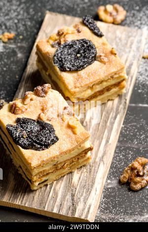 Gâteau aux pruneaux et noix. Morceaux de délicieux gâteau sur une assiette en bois. Décoration pour la table du nouvel an et de Noël. Banque D'Images