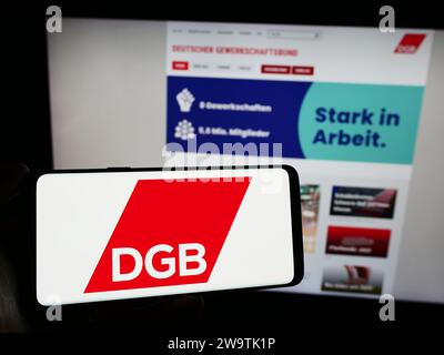 Personne tenant un smartphone avec le logo de l'organisation allemande Deutscher Gewerkschaftsbund (DGB) devant le site Web. Concentrez-vous sur l'affichage du téléphone. Banque D'Images